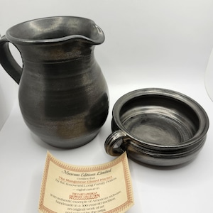 Op de afbeelding: Een zwarte en zilveren keramische kan en kom set. De set is handgemaakt en gesigneerd door de kunstenaar. Het label luidt "Museum Editions Limited certificeert dat de met mangaan geglazuurde kan van de gerenommeerde Long Family Potters - achtste uitgave in DE COLLECTIE VAN VROEGE AMERIKAANSE STEENGOED een authentiek voorbeeld is van Amerikaans aardewerk, handgemaakt in een 300 jaar oude traditie, een origineel kunstwerk en gesigneerd door de kunstenaar."