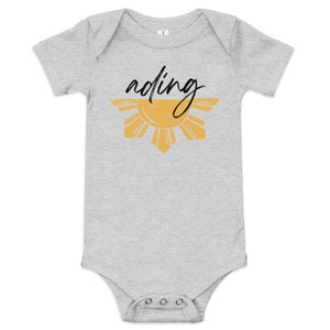 May include: A gray baby onesie with a yellow sun and the word "ading" written in black.