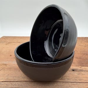 May include: A white ceramic mug with a black handle and the text "But First, Coffee" in a black, bold font. The mug is on a white surface.