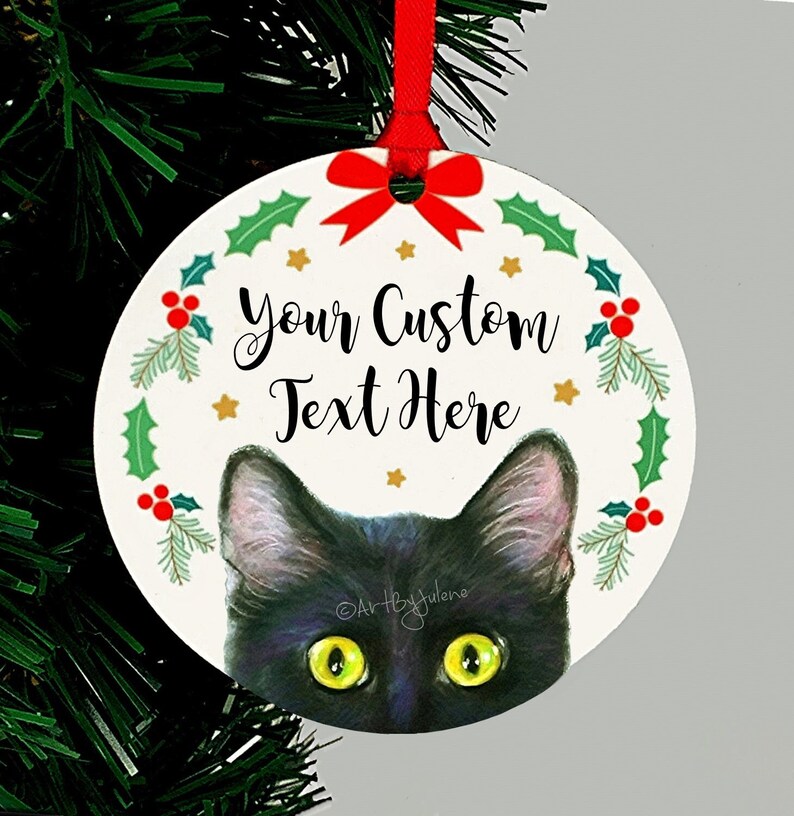 May include: A round Christmas ornament featuring a black cat peeking out from behind a green holly wreath with red berries. The ornament has a white background with gold stars and the text "Your Custom Text Here".