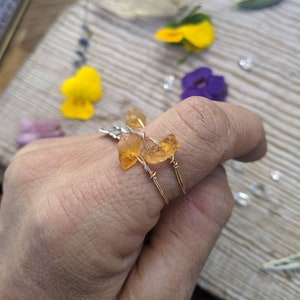 May include: Two gold rings with orange gemstone accents. The rings are made with wire wrapped around the stones.