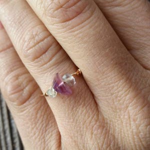 May include: A delicate ring made with wire and featuring a small purple and clear gemstone.