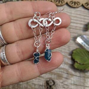 May include: Silver infinity symbol earrings with a dangling blue apatite crystal on each earring.