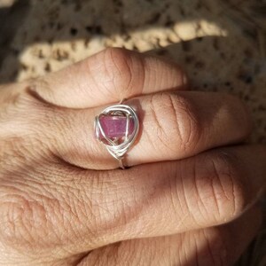 May include: A silver wire wrapped ring with a pink gemstone.