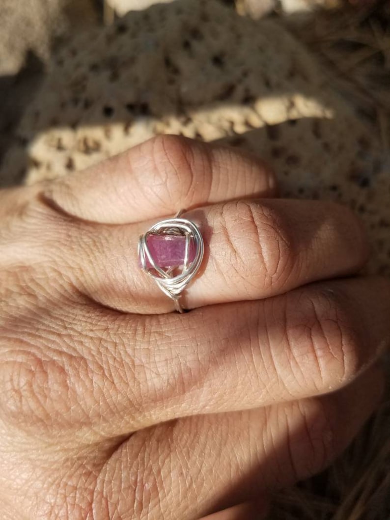 May include: A silver wire wrapped ring with a pink gemstone.
