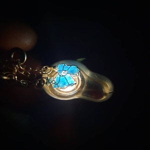 May include: A silver pendant necklace with a blue glass flower charm. The pendant is hanging from a silver chain.