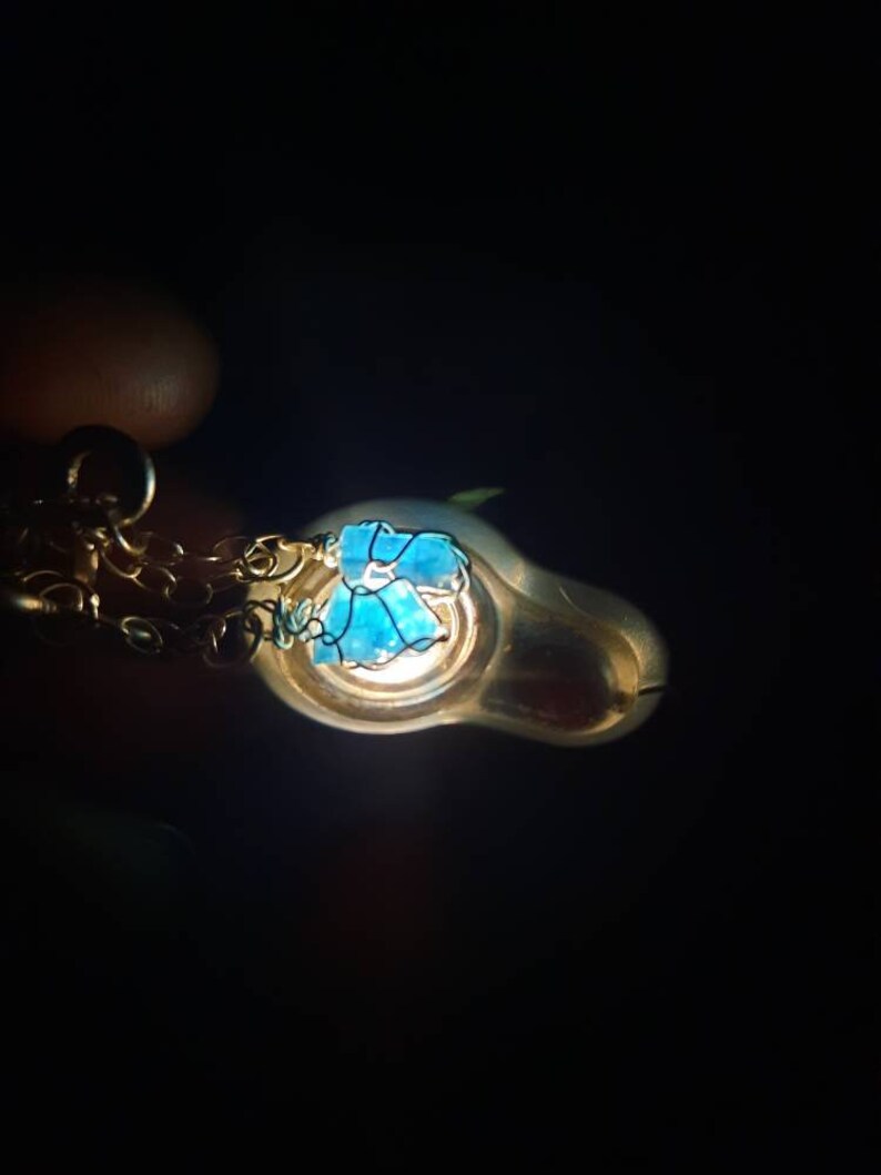 May include: A silver pendant necklace with a blue glass flower charm. The pendant is hanging from a silver chain.