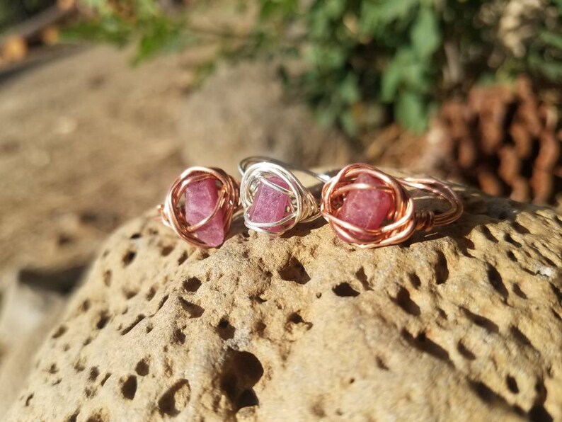 May include: Three wire-wrapped rings with pink gemstones. The rings are made with copper and silver wire.