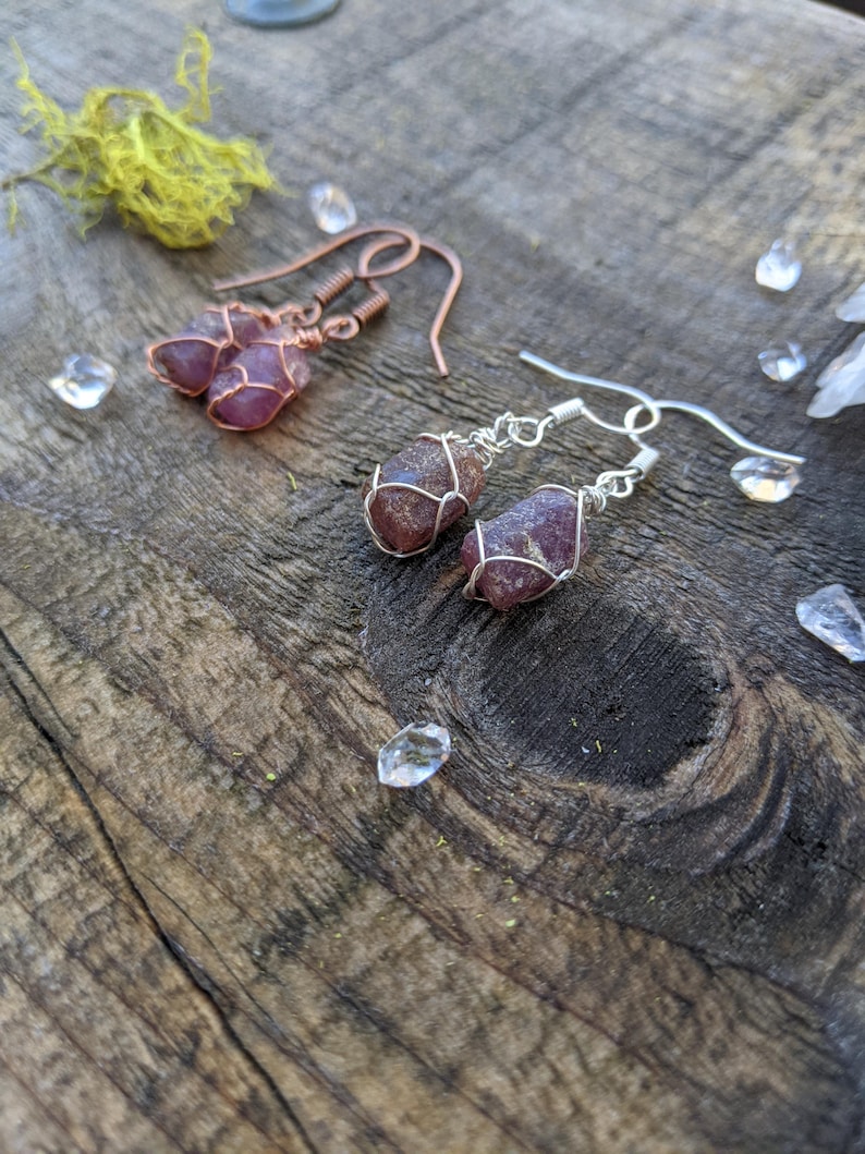 K&ouml;nnte beinhalten: Zwei Paar Ohrringe mit rosa und violetten Kristallsteinen, die in Draht gewickelt sind. Ein Paar hat Kupferdraht und das andere Silberdraht.