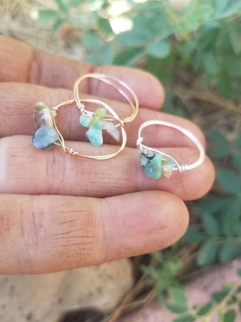 May include: Three gold rings with green and blue gemstone accents. The rings are made with wire and feature different sized gemstones.