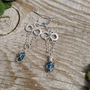 May include: A pair of silver earrings with infinity symbol charms and blue crystal accents.