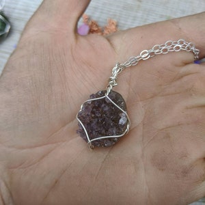May include: A silver chain necklace with a purple amethyst crystal pendant wrapped in silver wire.