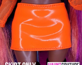 May include: A bright orange, shiny, faux leather mini skirt with a stitched hem.  The skirt is a fashion accessory for dolls.
