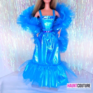 May include: A blue iridescent dress with a ruffled skirt and a matching blue feathered shawl. The dress has a fitted bodice with a blue belt.