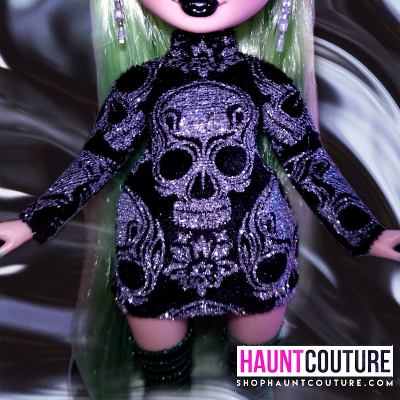 May include: A black and silver glittery dress with a skull design. The dress has long sleeves and a high neck. The dress is worn by a doll with green hair.