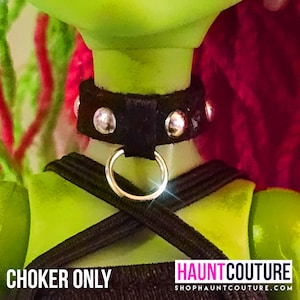Könnte beinhalten: Schwarzes Choker-Halsband mit silbernen Nieten und einem silbernen Ring. Das Choker ist aus Kunstleder und hat einen Punk-Rock-Look.