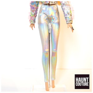 May include: Silver iridescent leggings with a holographic sheen. The leggings are on a doll stand. The text "HAUNT COUTURE" is in the bottom right corner of the image.