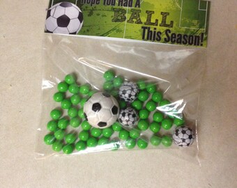 May include: A clear plastic bag filled with green candy and small soccer balls. The bag has a printed tag that says "Hope you had a ball this season!"