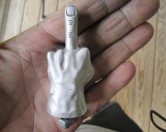 May include: A silver metal sculpture of a hand giving the middle finger.