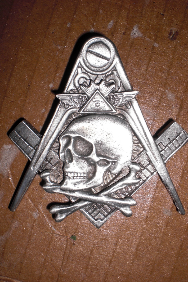 May include: A silver-toned metal Masonic pendant featuring a skull and crossbones, an all-seeing eye, and a compass and square.