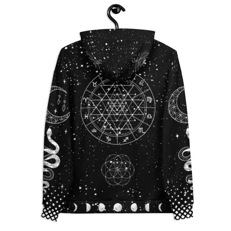 Peut inclure: Sweat-shirt &agrave; capuche noir avec un imprim&eacute; blanc d'un motif c&eacute;leste repr&eacute;sentant des symboles du zodiaque, des serpents et des lunes. Le motif est sur un fond noir avec un motif &eacute;toil&eacute; blanc.