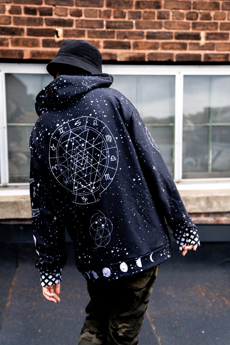 Peut inclure: Sweat-shirt noir avec un imprim&eacute; de constellation et de zodiaque blanc. Le sweat-shirt a une capuche avec cordon de serrage et un imprim&eacute; de phases de lune blanc sur l'ourlet inf&eacute;rieur.