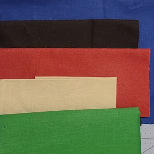 May include: A collection of fabric swatches in various colors, including blue, black, red, beige, and green. The fabric pieces are rectangular and arranged in a layered composition, showcasing the different hues and textures.