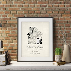 May include: Black and white print of a house-shaped map with a red door. The text "Charlotte & Andrew" is written below the map, along with coordinates and the date "12-18-2019". The text "Our First Home" is written below the date.