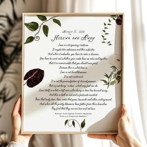 May include: A rectangular framed print featuring the text March 15, 2026, Helena and Andy, and an excerpt from Captain Corelli's Mandolin. The white background is decorated with watercolor illustrations of green leaves, vines, and dark red flowers.