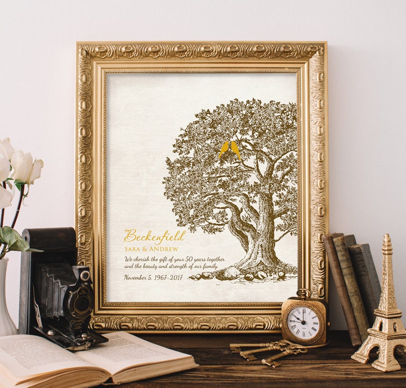 May include: A framed print with a gold frame and a white background. The print features a stylized drawing of a tree with two birds perched on a branch. The text "Beckenfield SARA & ANDREW We cherish the gift of your 50 years together and the beauty and strength of our family November 5, 1967-2017" is printed below the tree.