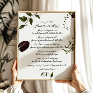 May include: A framed print featuring a wedding poem, with the names "Helena and Andy" and the date "March 15, 2026." The artwork includes watercolor floral and leaf accents in green, burgundy, and white. The text is in elegant script.