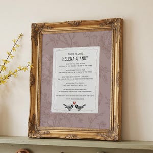 May include: A gold ornate frame containing a print with a mauve floral background. The central white paper features the text MARCH 15, 2026, HELENA & ANDY, and the Apache Marriage Blessing, finished with two small birds and a red heart icon.