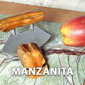 May include: A wooden apple corer with a stainless steel blade. The corer is made from manzanita wood and has a natural finish. The corer is sitting on a green and brown marble surface with a red apple next to it.