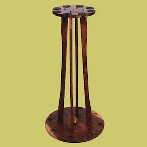 May include: A dark brown wooden pool cue rack with a circular base and eight slots for holding cues. The rack is made of solid wood and has a natural finish.