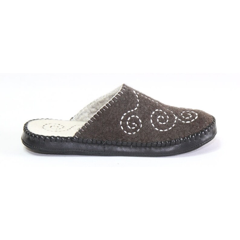 May include: Brown felt slippers with a white stitched swirl design and a black rubber sole.