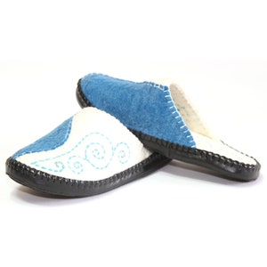 May include: A pair of blue and white felt slippers with a black rubber sole. The slippers have a decorative blue swirl design on the white side.