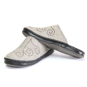 May include: A pair of gray felt slippers with a black rubber sole and a decorative swirl pattern. The slippers are made of soft, comfortable material and are perfect for keeping your feet warm.