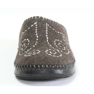 May include: A pair of brown felt slippers with white stitching in a decorative pattern. The slippers have a black leather sole.