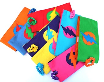 May include: A set of eight colorful felt headbands with a lightning bolt design. Each headband is a different color, including red, blue, green, yellow, orange, and pink. The headbands are decorated with a felt lightning bolt in a contrasting color.