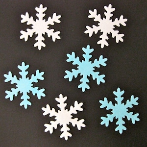 May include: Six snowflake cutouts in white and light blue are scattered on a dark background. The snowflakes have intricate, symmetrical designs, ideal for winter-themed crafts or decorations. The colour palette is simple and clean.
