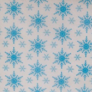 May include: A repeating pattern of blue snowflakes on a white background. The snowflakes vary in size and shade, creating a winter or festive theme. The design is symmetrical and evenly spaced.