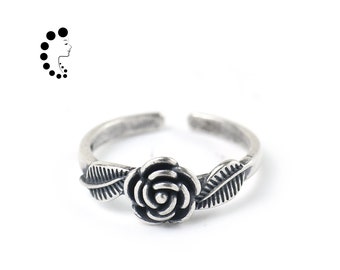 May include: An adjustable silver-toned ring featuring a central rose flower motif flanked by two detailed leaves on either side. The metal has an oxidised finish that highlights the engraved textures of the petals and the veins of the leaves.