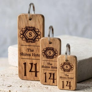 May include: Three wooden keychains with metal rings. Each keychain has the text "The Shires Hotel" and the number "14" engraved. The keychains also feature an ornate design with the letter "S".