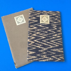 May include: Two brown paperbound books with the title "The Perpetuum Mobile" printed on the front cover. The book on the right has a blue and white patterned cover.