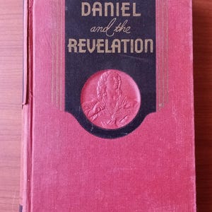 May include: A red hardcover book with a black spine and gold lettering. The title is "Daniel and the Revelation".