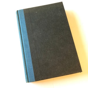 Puede incluir: Un libro de tapa dura con una cubierta negra y un lomo azul. El libro es rectangular y parece estar cerrado. El lomo es de un tono azul m&aacute;s claro que la cubierta.