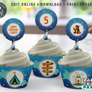 May include: Blue and white cupcake wrappers with a camping theme. The wrappers feature a tent, a lantern, and stars. The cupcake toppers are round and feature a bear playing a guitar, a number 5, and the text "Happy Birthday Corey!"