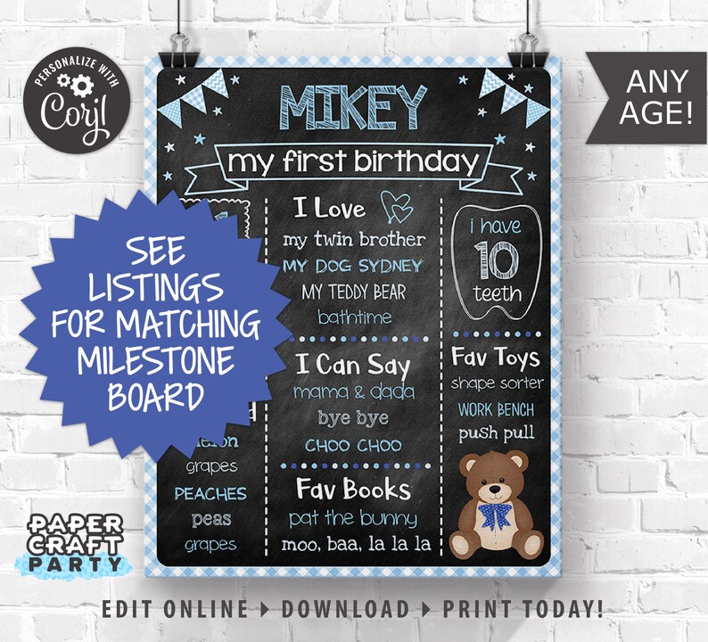 May include: A blue and white chalkboard style birthday sign with the name Mikey and the text "my first birthday". The sign lists milestones such as "I love", "I can say", "Fav toys", and "Fav books".