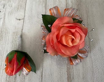 Corsage and matching boutonnière in coral roses trimmed in tangerine and silver