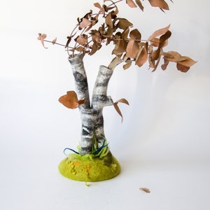 May include: A felt sculpture of a birch tree with brown branches and a green base. The tree is made of felt and has a realistic appearance.
